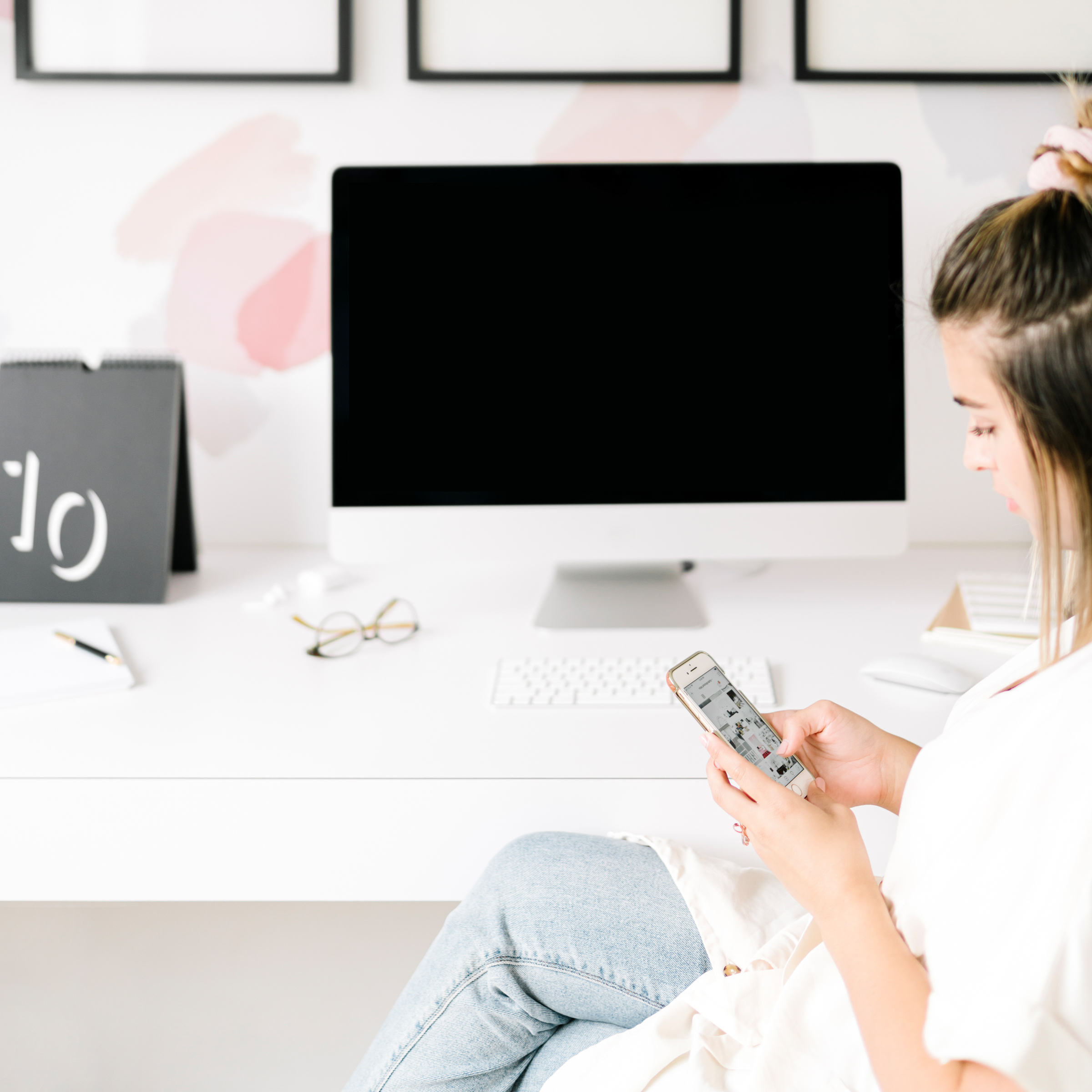 Frau prokrastiniert am Handy im Arbeitszimmer